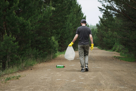 Man collecting plastic garbage on a forest path outdoors