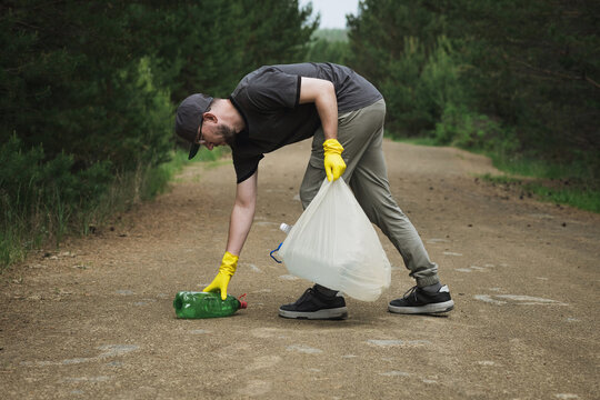 Volunteer collecting plastic garbage on forest road