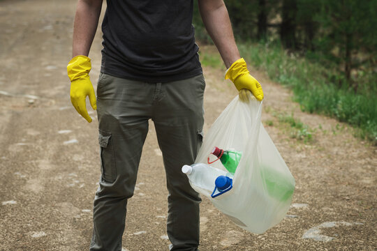 Volunteer holding plastic trash bag during forest cleanup