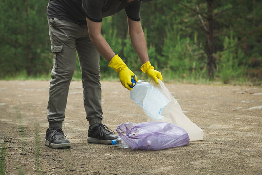 Volunteer collecting plastic garbage on forest trail cleanup