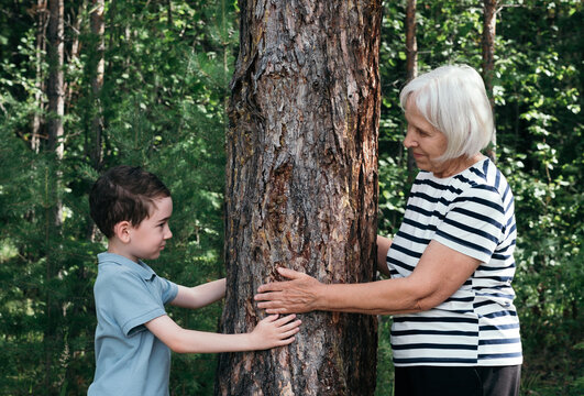 Portrait of grandmother and grandson hugging a tree outdoors