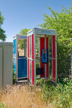 Vintage red and blue phone booths surrounded by weeds in Shantytown, Nevada, USA