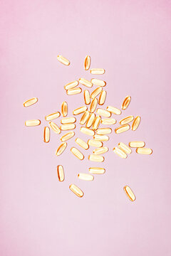 Scattered softgel capsules on a pastel background