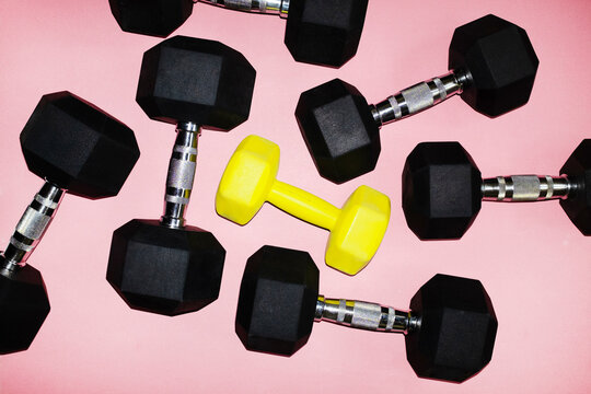 Set of black and yellow dumbbells on pink background