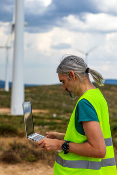 Wind farm engineer using laptop to monitor turbine data