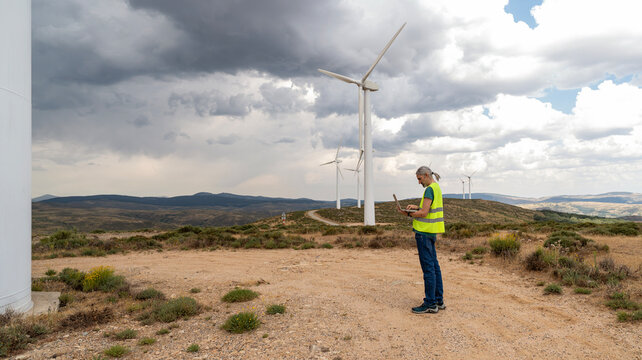 Wind farm technician inspecting turbine performance outdoors