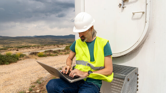 Field technician using laptop at renewable energy site