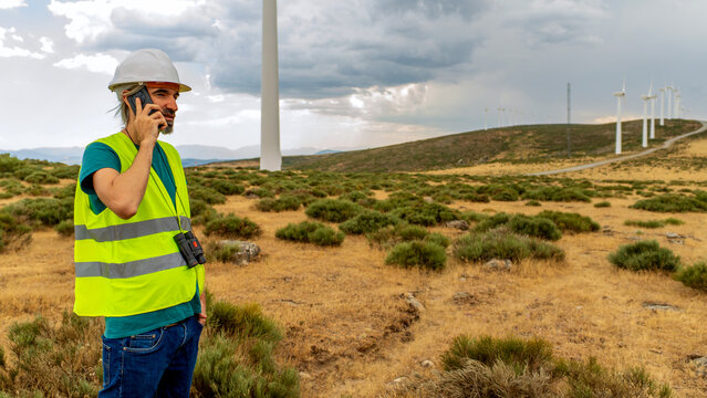 Wind farm technician talking on phone during inspection