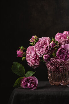 Pink rose bouquet in glass vase on dark background