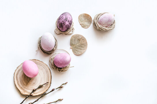 Pastel Easter eggs in nests with leaves on white