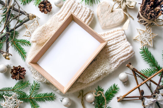 Cozy Christmas flat lay with mitten and blank wooden frame