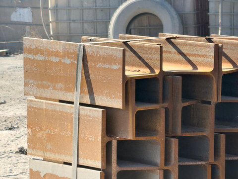 Stacked steel I-beam bundle strapped in an industrial yard