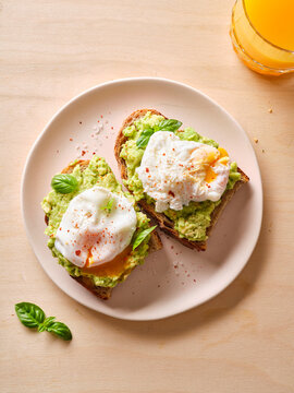 Avocado sandwich with poached eggs and juice on plate