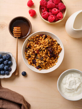 Granola breakfast with berries and honey on wooden table