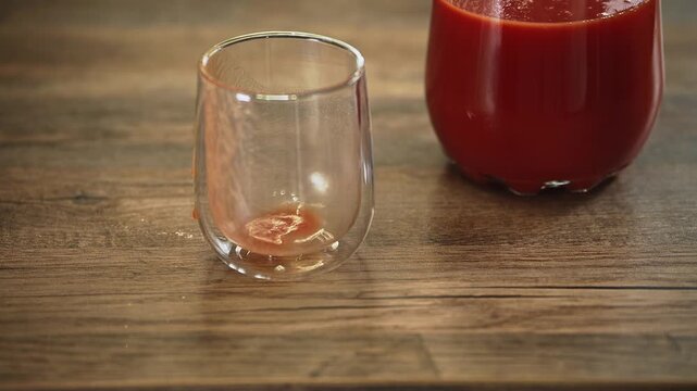 A simple beverage setup featuring a pitcher of rich tomato juice beside an empty glass. The bright natural setting creates a fresh food lifestyle scene focused on healthy drinks, homemade nutrition.
