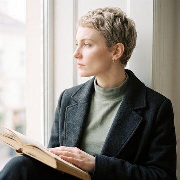 Generative AI, Woman reading book and looking out window thoughtfully