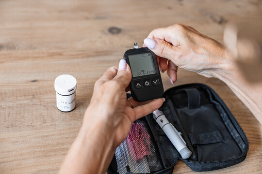 Person using glucose meter with diabetes test kit at home