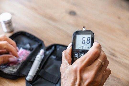 Hand holding glucometer showing blood sugar level at home