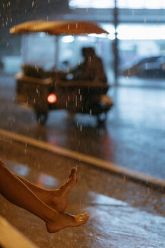 Bare feet in rain with blurred motorcycle passing at night