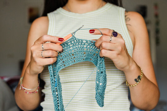 Close-up of woman crocheting lace pattern with blue yarn