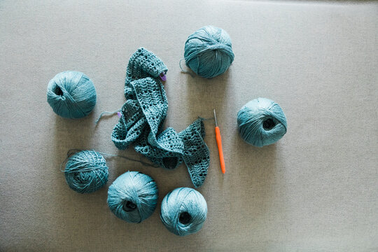 Flat lay crochet project with blue yarn balls and hook