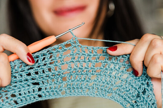 Close-up of woman crocheting blue lace fabric by hand