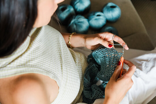 Person crocheting lace textile with blue yarn at home