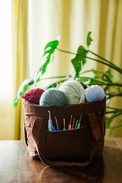 Crochet bag with yarn balls and hooks on wooden table