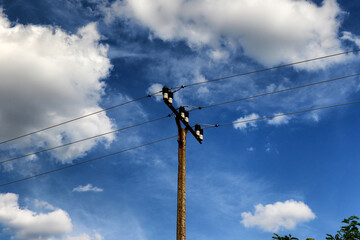 Obraz premium Old utility pole with wires against cloudy blue sky