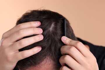Fototapeta premium Man combing his hair on beige background, closeup