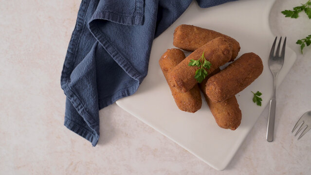 Crispy fried croquettes on a white plate with a blue cloth