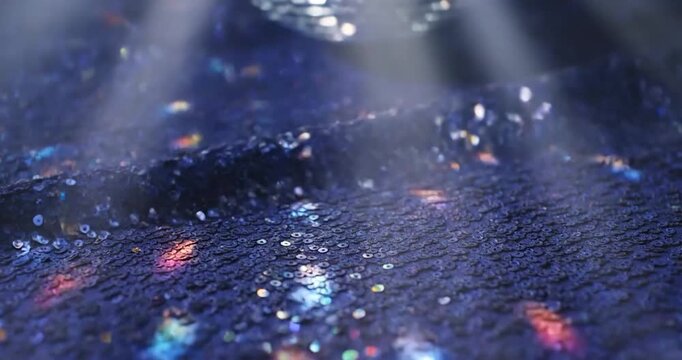 Dark blue sequin fabric background with light reflections and sparkles