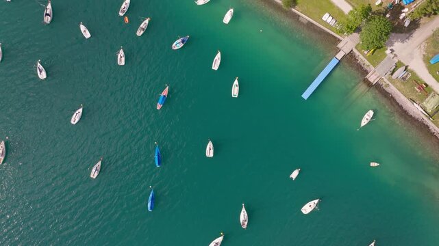Top down aerial view of sailboats anchored in turquoise water at Lake Achensee
