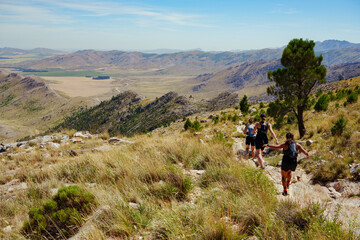 Fototapeta premium group of three Female Trail Runners running on a stone trail with a scenic arid mountain view