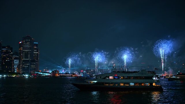 Blue fireworks display over New York City at night. Passengers watch bright azure pyrotechnic bursts from a large passenger vessel on the river during the holiday.