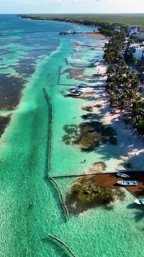 Vertical drone view of boats anchored on Mahahual beach with turquoise sea and sargassum barrier in Mexico on a clear day