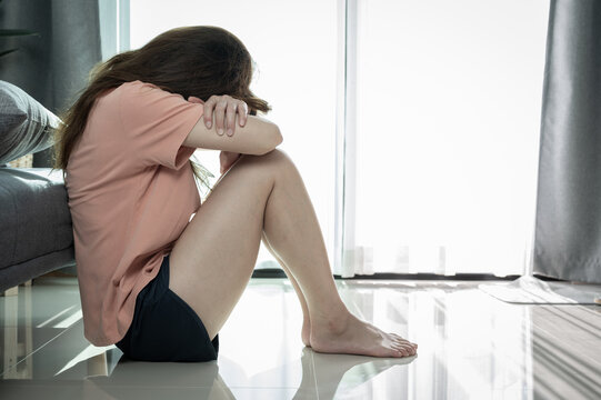 Depressed woman sitting alone in living room caused of sadness or broken heart. Depression is a form of highly negative thinking towards oneself, others and life.