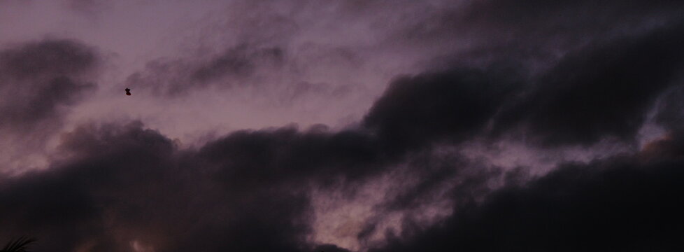 Moody purple dusk sky with dark storm clouds rolling in during a dramatic autumn evening