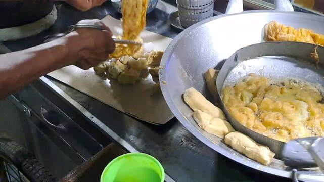 Indonesian street vendor making Tahu Tek Telur. Process includes whisking egg, frying omelette and tofu, cutting lontong with scissors, and making peanut petis sauce. Authentic Surabaya street food.