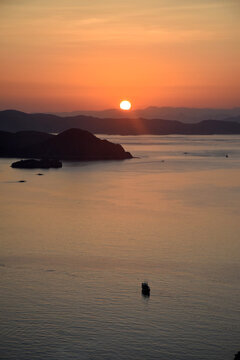 A sunrise with beautiful reddish-yellow light emerging between the hills surrounding Padar and Rinca Islands, Labuan Bajo, Indonesia.