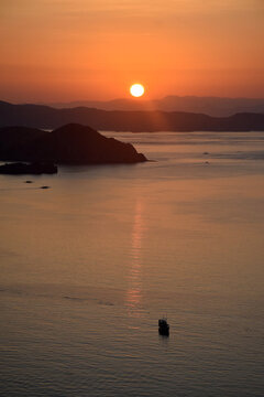 A sunrise with beautiful reddish-yellow light emerging between the hills surrounding Padar and Rinca Islands, Labuan Bajo, Indonesia.