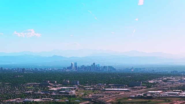 City of Denver downtown skyscrapers buildings cityscape aerial drone view Colorado cars traffic foothills Front Range Rocky Mountains layers summer spring blue skies morning smokey haze clouds forward