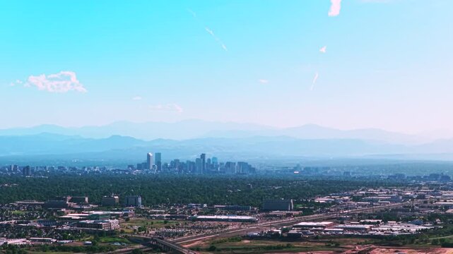 Smokey haze Front Range downtown cityscape city of Denver skyscrapers buildings Aerial drone view Colorado cars traffic foothills Rocky Mountains layers summer spring blue skies morning pan left
