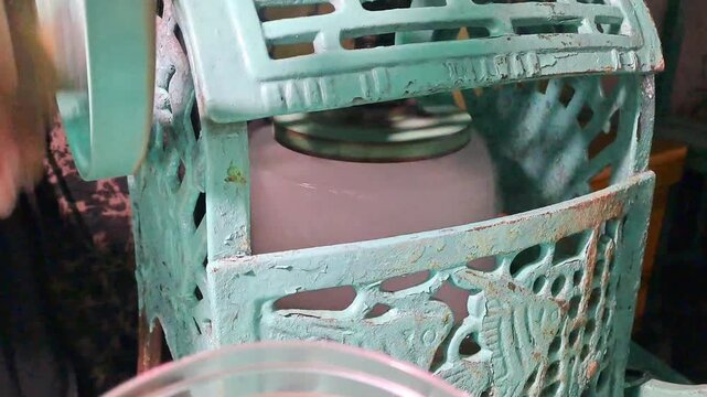 Indonesian vendor preparing Es Kacang Ijo for takeaway order. Process includes scooping mung beans into plastic, shaving ice with vintage manual machine, and pouring coconut milk. Street food cart.