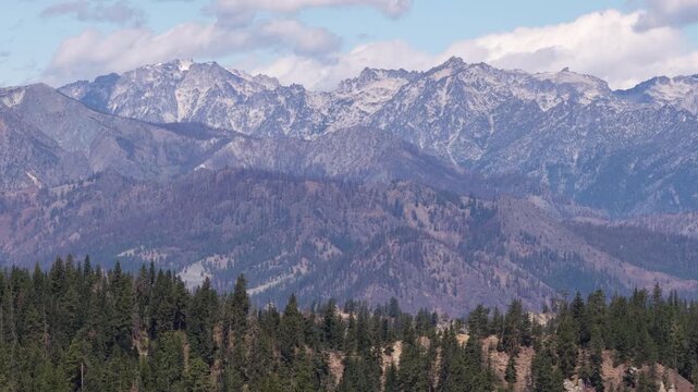 Aerial of Okanogan Wenatchee National Forest and Stuart Mountain Range with snow patches in summer with layers of mountains