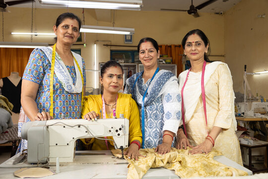 Skilled Indian women workers actively working inside a textile export house while looking directly at the camera. Professional female employees engaged in garment manufacturing, representing Skill Ind