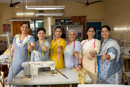 Skilled Indian woman worker standing inside a textile export house showing a thumbs-up gesture while looking at the camera. Confident female employee representing workplace success and quality