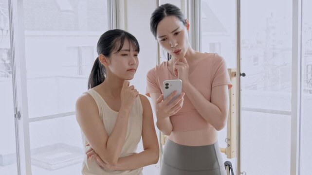 携帯を見て悩むスポーツウェアをきた女性