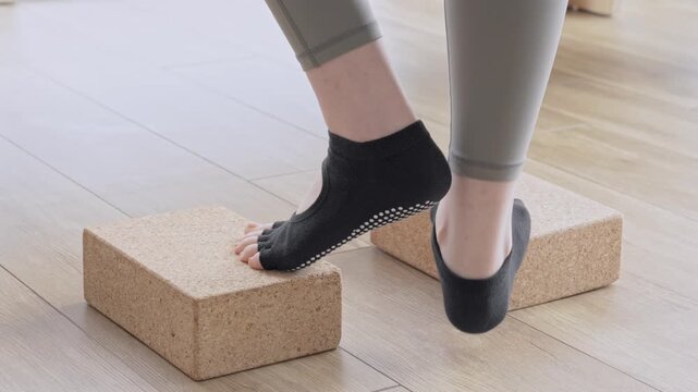 ヨガブロックを使ってヒールレイズ（かかと上げ）をする女性
