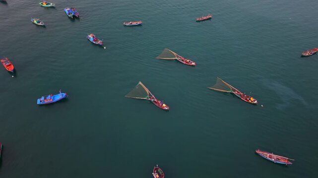 Aerial drone footage looking down at traditional Vietnamese fishing boats scattered across calm blue waters near Da Nang. Peaceful maritime scene with elegant boat patterns and minimal composition.